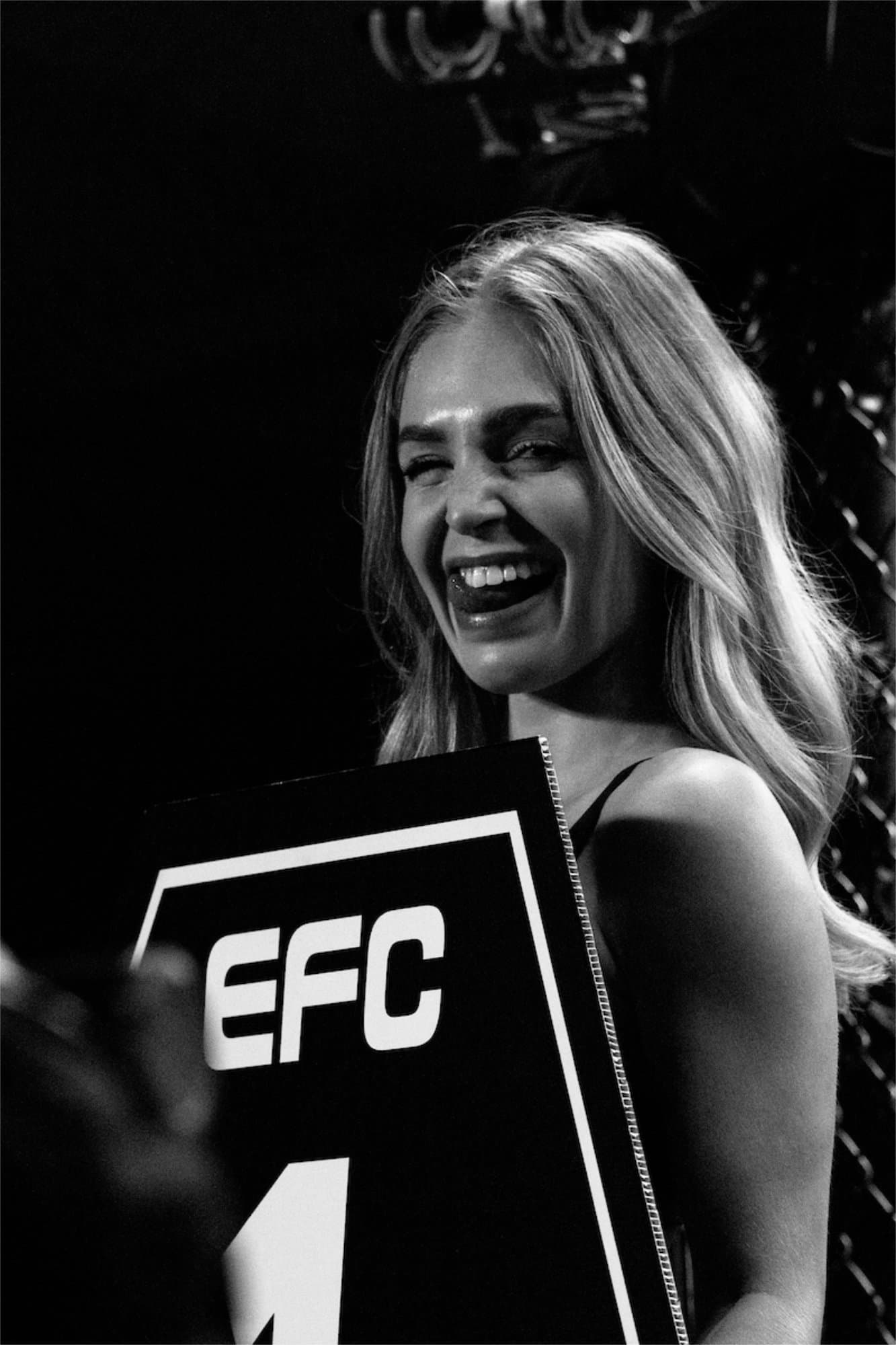 EFC ring girl laughing while holding the round card